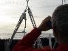 captain of sailboat watching oil tanker